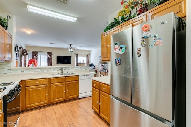 kitchen with freestanding refrigerator, white dishwasher, range with gas cooktop, a sink, and light wood-style floors