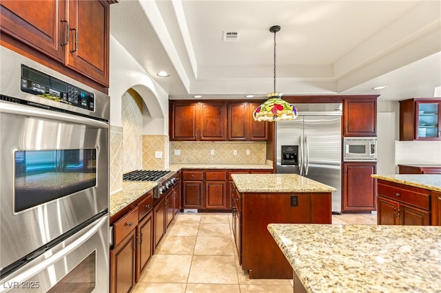 4542 Grey Spencer Dr, Las Vegas, NV 89141 - kitchen with built in appliances, decorative backsplash, a tray ceiling, a kitchen island, and light stone countertops