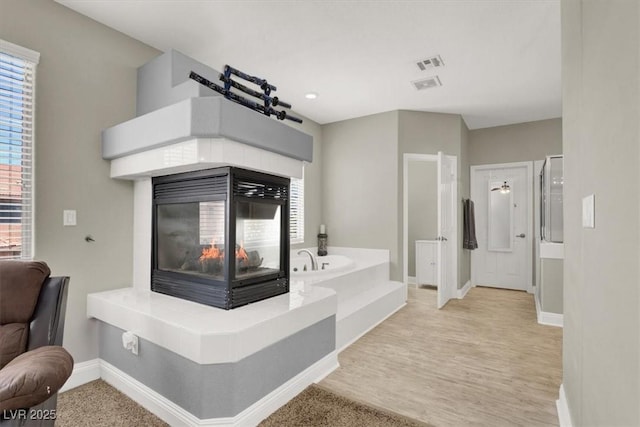 7310 Heggie Ave, Las Vegas, NV 89131 - full bathroom with a multi sided fireplace, baseboards, a bath, and healthy amount of natural light
