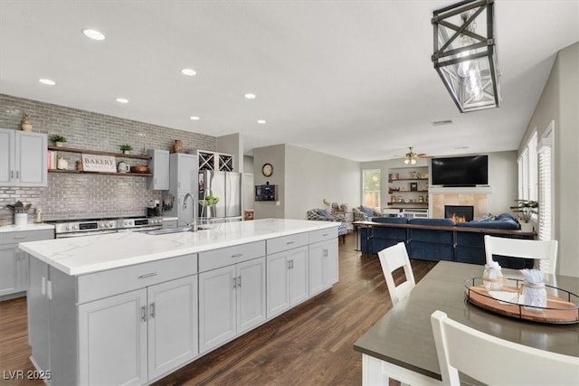 7310 Heggie Ave, Las Vegas, NV 89131 - kitchen featuring appliances with stainless steel finishes, a sink, a center island with sink, dark wood-style floors, and recessed lighting