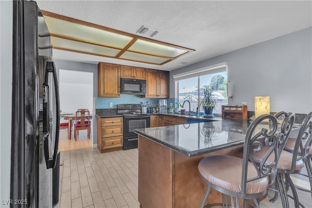 1808 Piccolo Way, Las Vegas, NV 89146 - kitchen featuring black appliances, a peninsula, a sink, brown cabinetry, and a breakfast bar area