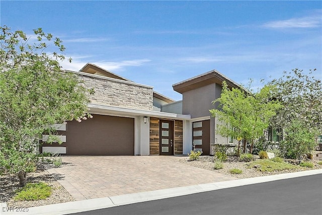 6184 Willow Rock St, Las Vegas, NV 89135 - contemporary house featuring an attached garage, decorative driveway, stucco siding, and stone siding