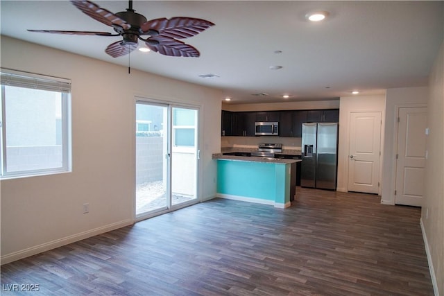 kitchen with appliances with stainless steel finishes, ceiling fan, a peninsula, dark wood finished floors, and recessed lighting