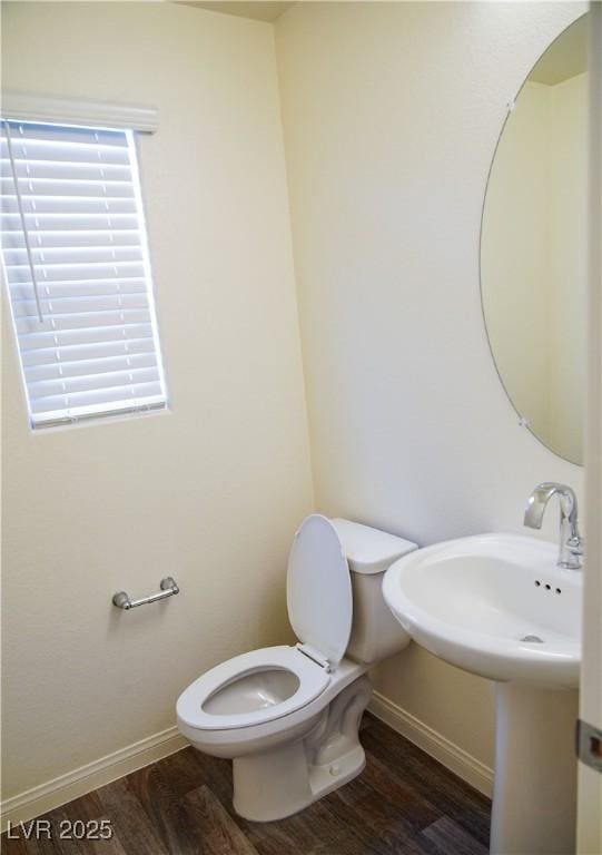 half bath with wood finished floors, toilet, and baseboards