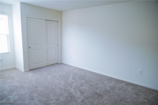 unfurnished bedroom with carpet flooring, multiple windows, a closet, and baseboards
