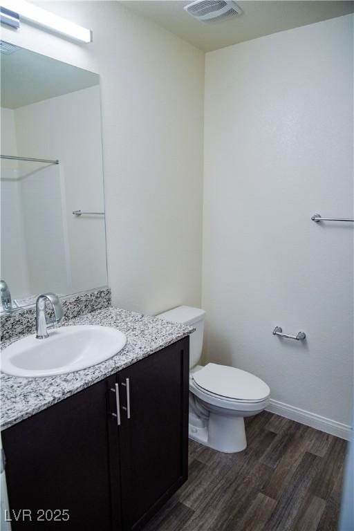 bathroom featuring wood finished floors, vanity, toilet, a shower, and baseboards