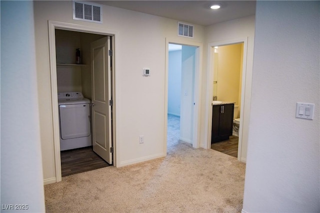 corridor featuring washer / dryer, carpet floors, and baseboards