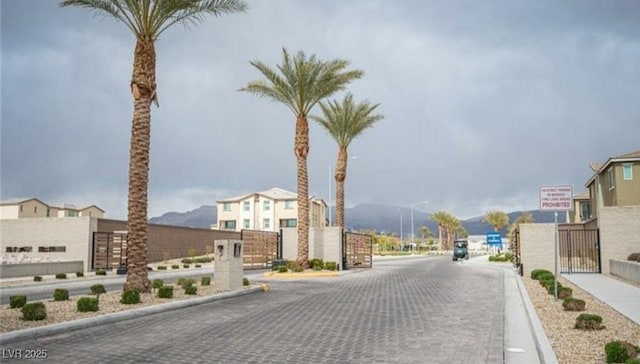 view of road with curbs, a gate, and street lights