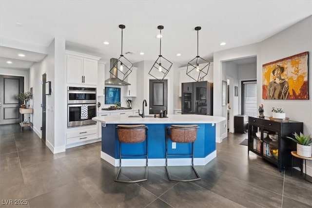 10954 Free Flow Pl, Las Vegas, NV 89138 - kitchen featuring wall chimney range hood, light countertops, appliances with stainless steel finishes, recessed lighting, and a center island with sink