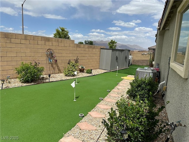 8269 Skye Peak St, Las Vegas, NV 89166 - fenced backyard with an area to practice putting, a storage shed, an outdoor structure, a mountain view, and central AC unit