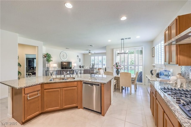 8269 Skye Peak St, Las Vegas, NV 89166 - kitchen with stainless steel appliances, a sink, open floor plan, light stone counters, and brown cabinetry