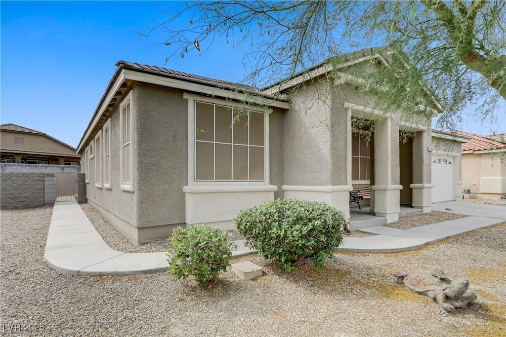 view of home's exterior featuring stucco siding, a garage, and fence
