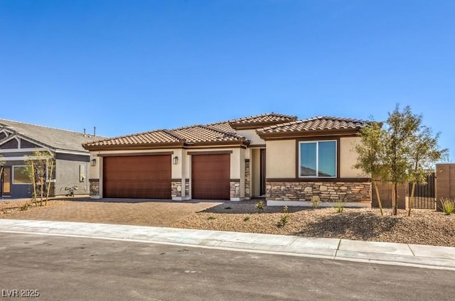 1220 Eva Creek Dr Unit 35, North Las Vegas, NV 89084 - view of front of home featuring stone siding, an attached garage, a tiled roof, and driveway