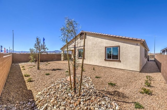1220 Eva Creek Dr Unit 35, North Las Vegas, NV 89084 - view of side of property featuring a fenced backyard, stucco siding, and a tiled roof