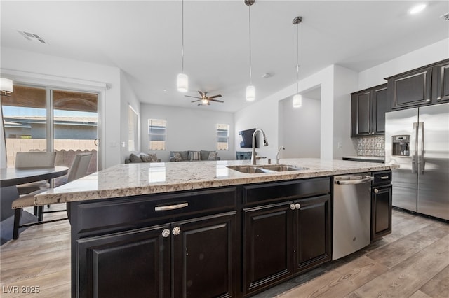 485 Pebble Run Ave, Henderson, NV 89011 - kitchen featuring stainless steel appliances, a sink, an island with sink, light wood-style flooring, and hanging light fixtures
