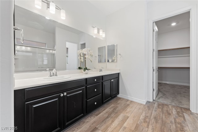 485 Pebble Run Ave, Henderson, NV 89011 - bathroom with wood finished floors, double vanity, an enclosed shower, a walk in closet, and baseboards
