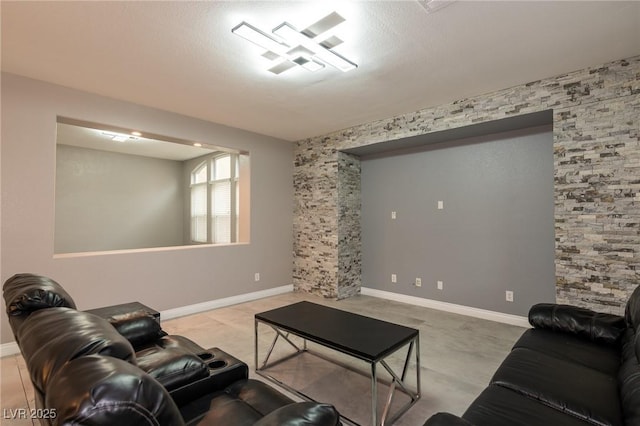 living area with baseboards and an accent wall