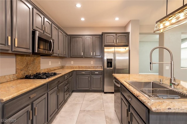 kitchen with stainless steel appliances, a sink, decorative light fixtures, recessed lighting, and light stone counters