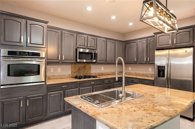 kitchen with appliances with stainless steel finishes, a sink, recessed lighting, an island with sink, and decorative light fixtures
