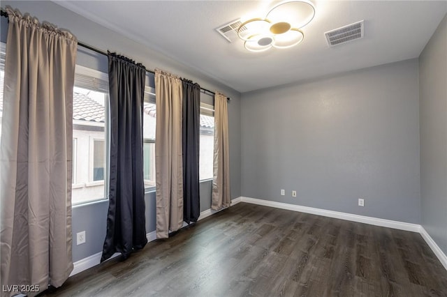 spare room featuring dark wood-type flooring, baseboards, and a chandelier