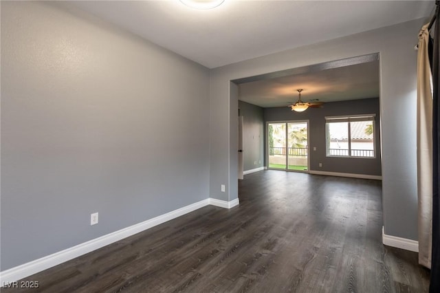unfurnished room featuring baseboards, dark wood finished floors, and ceiling fan