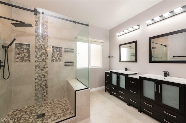 bathroom featuring a shower stall, two vanities, and baseboards