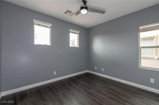 unfurnished room featuring dark wood finished floors, a ceiling fan, and baseboards