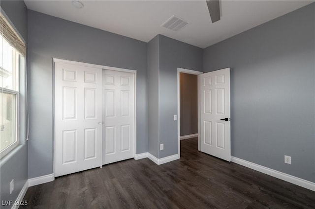unfurnished bedroom with dark wood finished floors, baseboards, and a closet