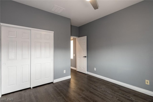 unfurnished bedroom with dark wood-style floors, baseboards, a closet, and a ceiling fan