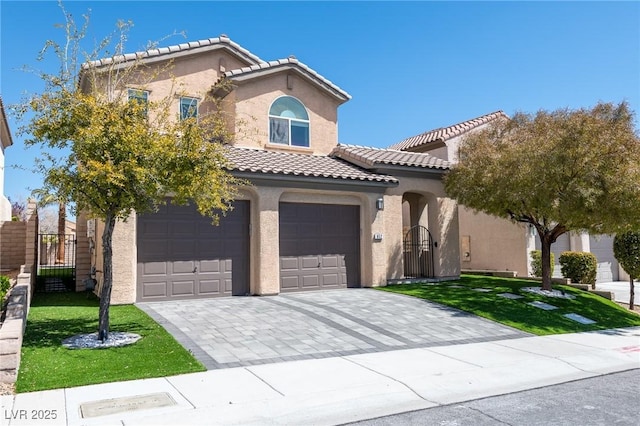 mediterranean / spanish-style home featuring stucco siding, a tiled roof, an attached garage, decorative driveway, and a gate