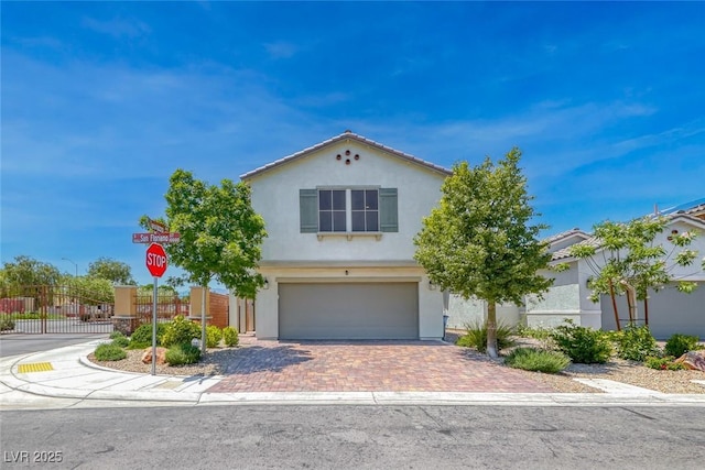 view of front of home featuring a garage, decorative driveway, stucco siding, and fence