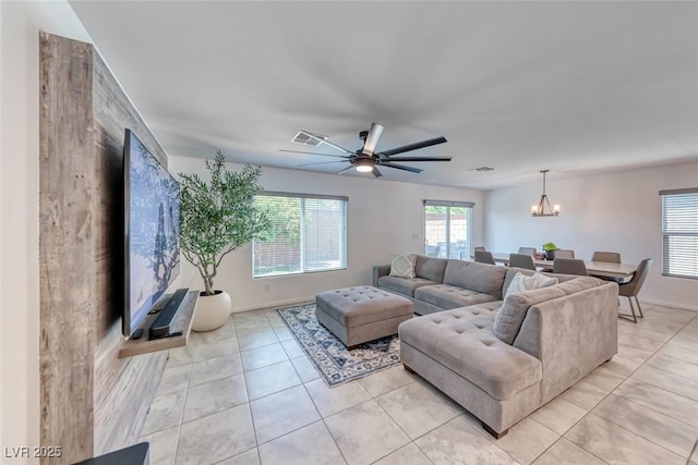living room featuring light tile patterned floors, a chandelier, a ceiling fan, and baseboards