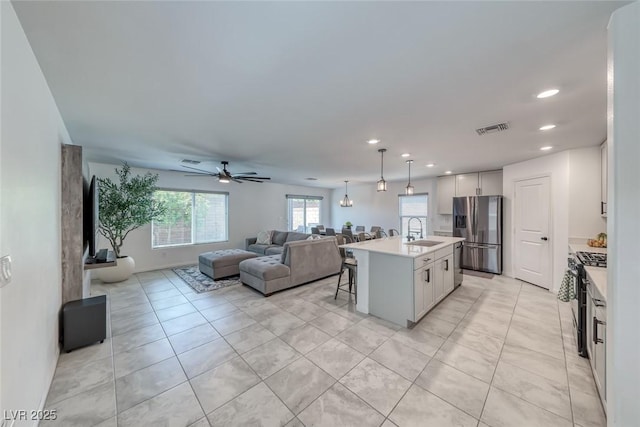 kitchen featuring appliances with stainless steel finishes, open floor plan, a sink, a kitchen breakfast bar, and light countertops