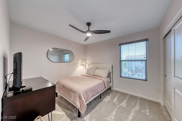 bedroom featuring light carpet, baseboards, ceiling fan, and a closet