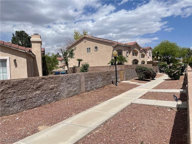 view of property exterior featuring stucco siding, fence, and a tile roof