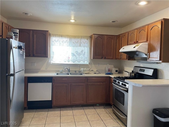 kitchen featuring stainless steel appliances, a sink, under cabinet range hood, light countertops, and light tile patterned floors
