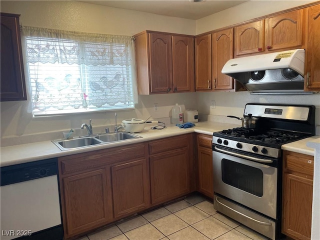 kitchen featuring stainless steel range with gas stovetop, under cabinet range hood, white dishwasher, a sink, and light countertops