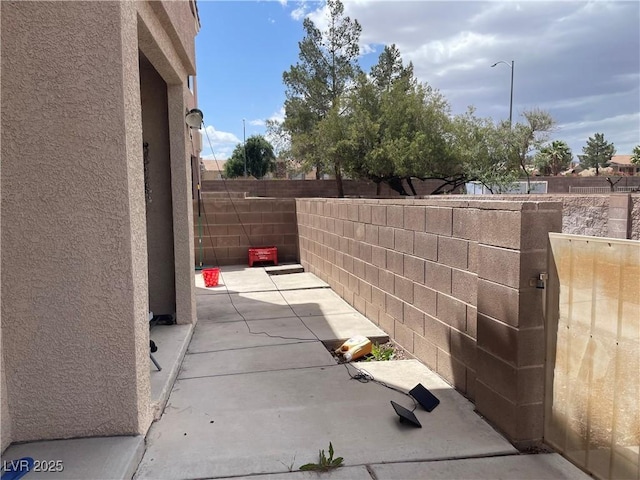 view of side of home with stucco siding, fence, and a patio area
