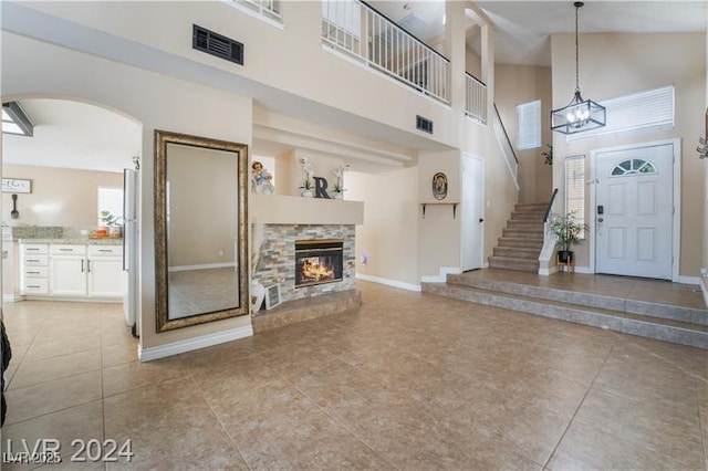 4209 Glass Lantern Dr, North Las Vegas, NV 89032 - foyer entrance featuring a high ceiling, light tile patterned floors, arched walkways, a stone fireplace, and baseboards