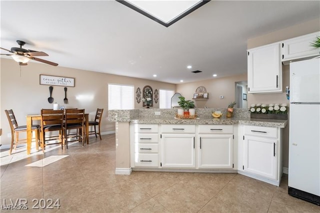 4209 Glass Lantern Dr, North Las Vegas, NV 89032 - kitchen featuring freestanding refrigerator, a peninsula, a ceiling fan, white cabinets, and light tile patterned floors