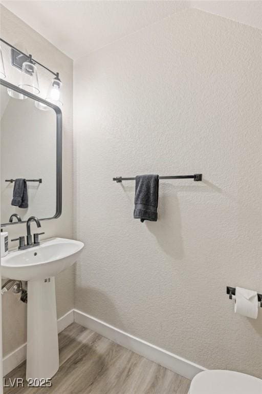 bathroom with baseboards, wood finished floors, and toilet