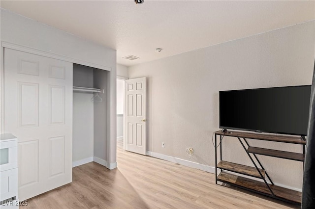 unfurnished bedroom with light wood-type flooring, baseboards, and a closet