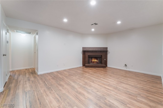 6711 W Charleston Blvd Unit 2, Las Vegas, NV 89146 - unfurnished living room with light wood-type flooring, a brick fireplace, recessed lighting, and baseboards