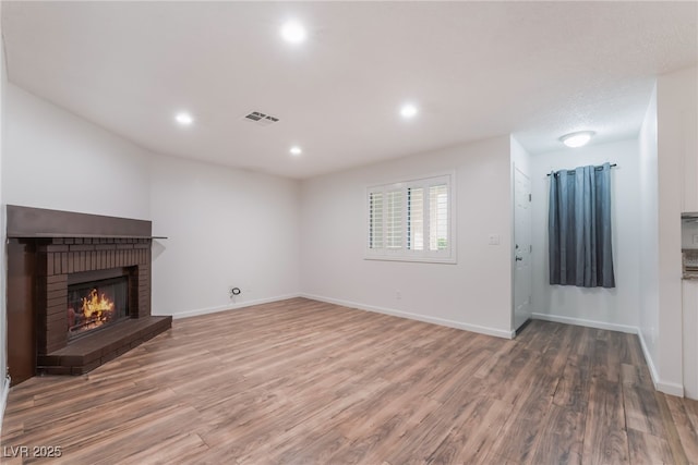 6711 W Charleston Blvd Unit 2, Las Vegas, NV 89146 - unfurnished living room featuring wood finished floors, a fireplace, recessed lighting, and baseboards