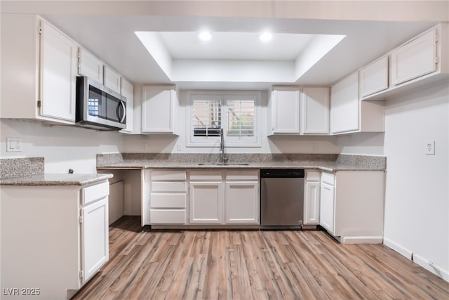 6711 W Charleston Blvd Unit 2, Las Vegas, NV 89146 - kitchen with appliances with stainless steel finishes, a sink, a tray ceiling, light wood finished floors, and white cabinets