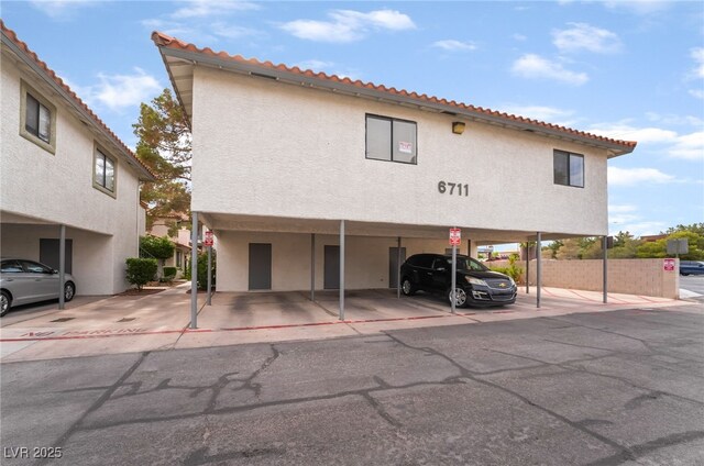 6711 W Charleston Blvd Unit 2, Las Vegas, NV 89146 - view of front of property featuring covered parking, a tile roof, stucco siding, and fence