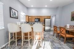1012 Greystone Dr, Las Vegas, NV 89108 - kitchen featuring freestanding refrigerator, brown cabinetry, a peninsula, recessed lighting, and a kitchen bar
