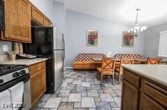 1012 Greystone Dr, Las Vegas, NV 89108 - kitchen with stainless steel gas stove, a chandelier, light stone finish floors, and light countertops