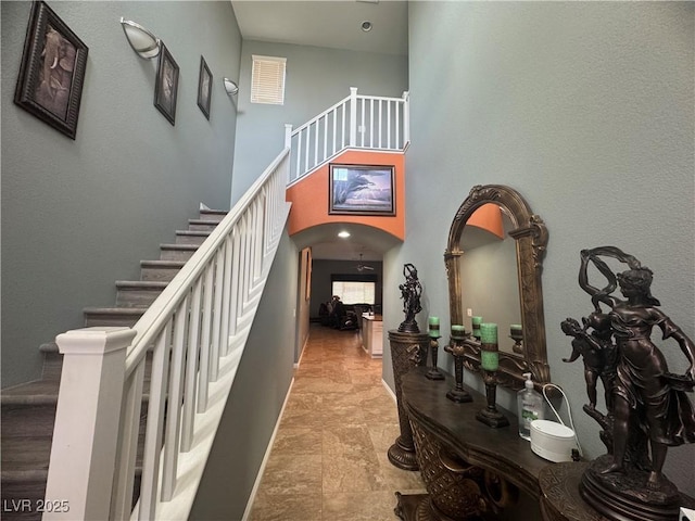 640 House Blend Ln, Henderson, NV 89052 - hallway with arched walkways, stairway, a high ceiling, and stone finish flooring