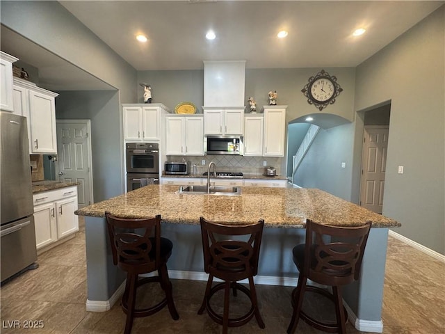 640 House Blend Ln, Henderson, NV 89052 - kitchen with stainless steel appliances, decorative backsplash, a center island with sink, white cabinets, and recessed lighting